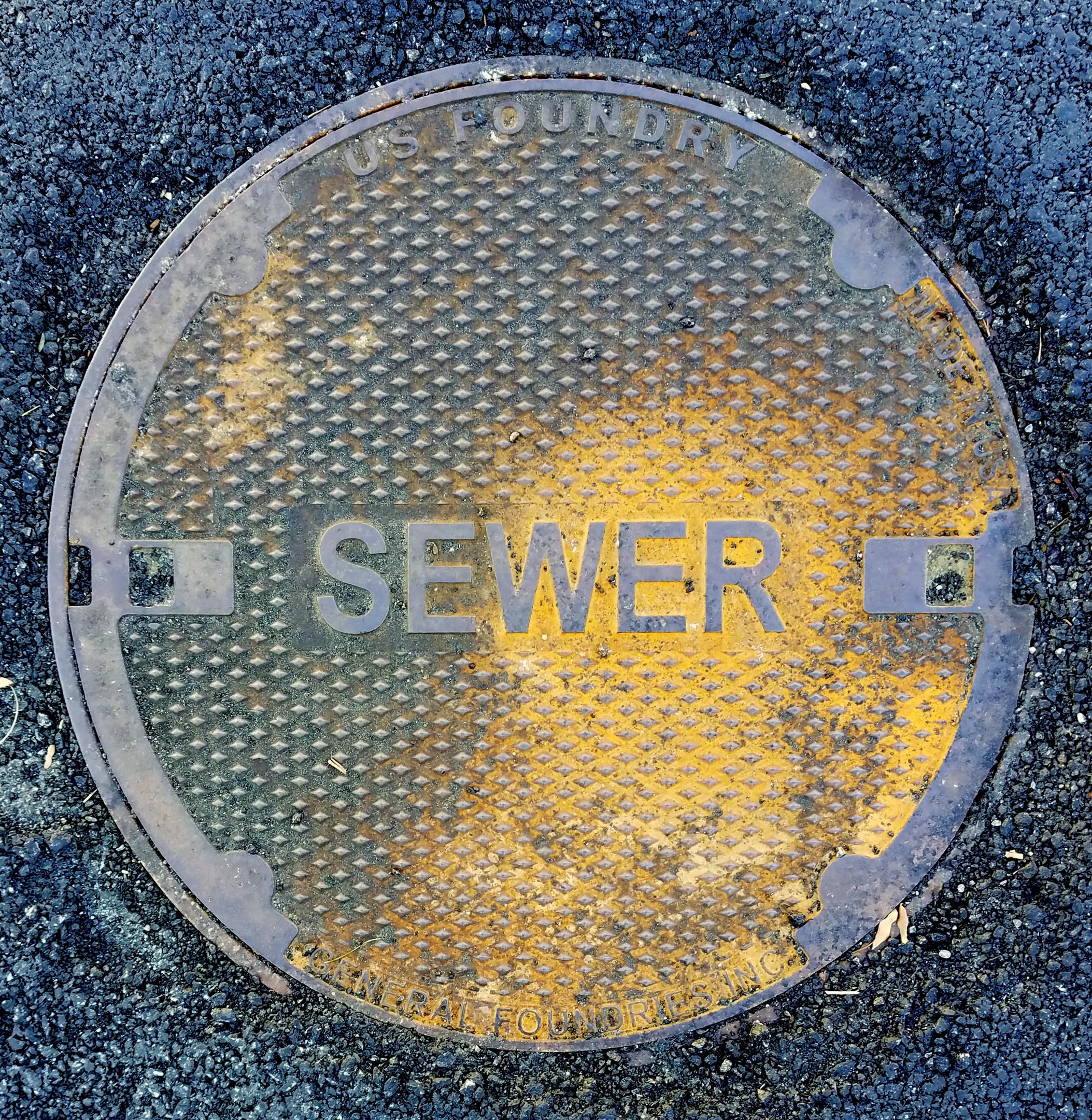 Metallschachtdeckel auf einer Straße mit der Aufschrift "Kanal"