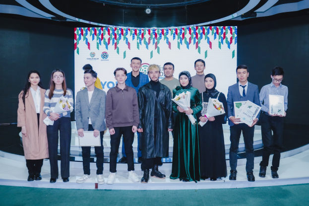 Eine Gruppe von Menschen auf einer Bühne mit Blumensträußen und Urkunden, im Hintergrund ein "Jugend-Solar-Awards 2019"-Plakat.