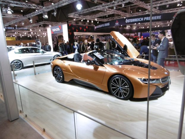 Ein glänzendes schwarzes BMW i8 Cabrio mit Chromakzenten auf der Frankfurt Motor Show umgeben von formell gekleideten Besuchern.
