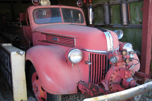 Ein Kraftfahrzeug steht auf einem stein├╝ber├Ąckerten Boden mit Feuerl├Âschern an der benachbarten Wand montiert.