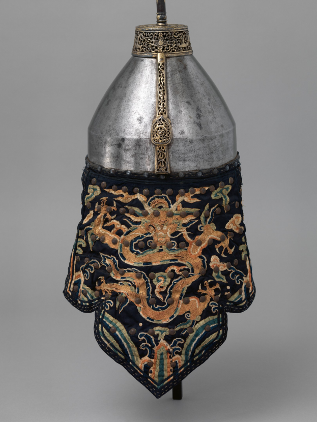 Metallhelm mit einer Drachengestaltung, vor einem grauen Hintergrund.