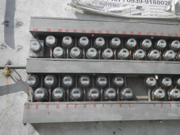 Nahaufnahme eines Elektrizitätszählers an der Seite eines Gebäudes mit einem Banner oben mit Text