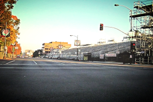 Eine Straße mit einem Verkehrssignalmast und Gerät auf der rechten Seite, Warnschilder und mehrere Fahrzeuge vor zahlreichen Bäumen auf der linken Seite.