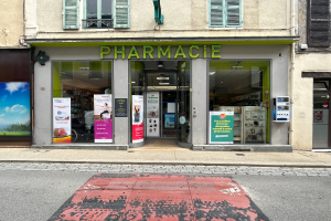 Eine Apotheke an einer Straßenecke mit Glaswänden und -türen, Plakate an den Wänden und einer Straße davor.