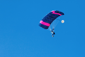 Eine Person beim Paragleiten mit einem klaren Himmel im Hintergrund.