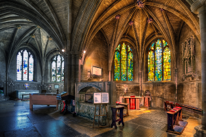 Ein Raum mit Bänken, Tischen, einer Tafel, Kerzen, einem Kamin und Lichtern, mit Fenstern auf beiden Seiten, bearbeitet.