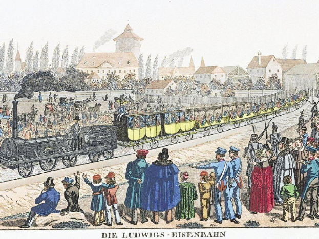 Eine Gruppe von Menschen, die um einen Zug auf Schienen stehen, einige sitzen im Zug und andere auf dem Boden, vor einem Hintergrund aus Gebäuden und Bäumen, mit Text unten, der "Ludwigs-Eisenbahn, der erste Bahnhof Deutschlands" lautet.