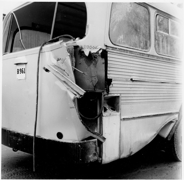 Schwarz-weißes Foto eines Busses mit schwerer Frontschaden nach einem Autounfall auf der Straße.