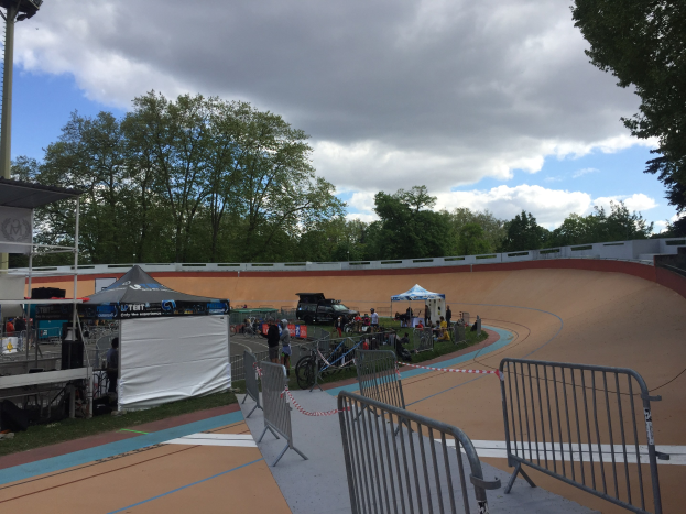 Gruppe von Radfahrern auf einer Schotterstrecke bei den UCI BMX-Weltmeisterschaften 2018, mit Zuschauern, Zelten und Bäumen im Hintergrund.