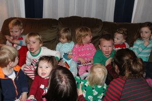 Eine Gruppe von Kindern sitzt auf einem Sofa in einem Raum, jeder hält ein Mobiltelefon, mit einer Frau rechts und einem Vorhang oben im Bild.