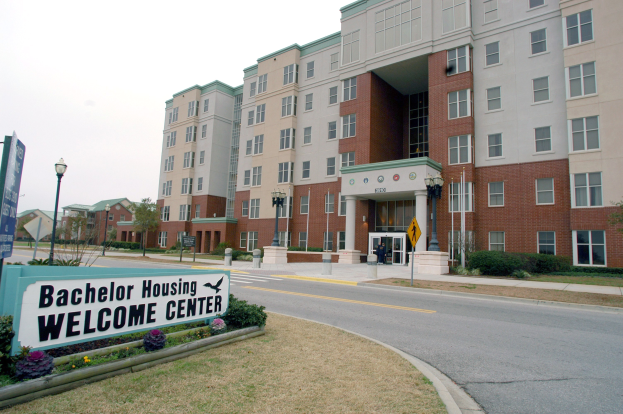 Ein Willkommenszentrum für Bachelor-Unterkünfte mit Geb├Ąuden, Stra├čeninfrastruktur, Fahrzeugen, Vegetation und einem klaren Himmel.