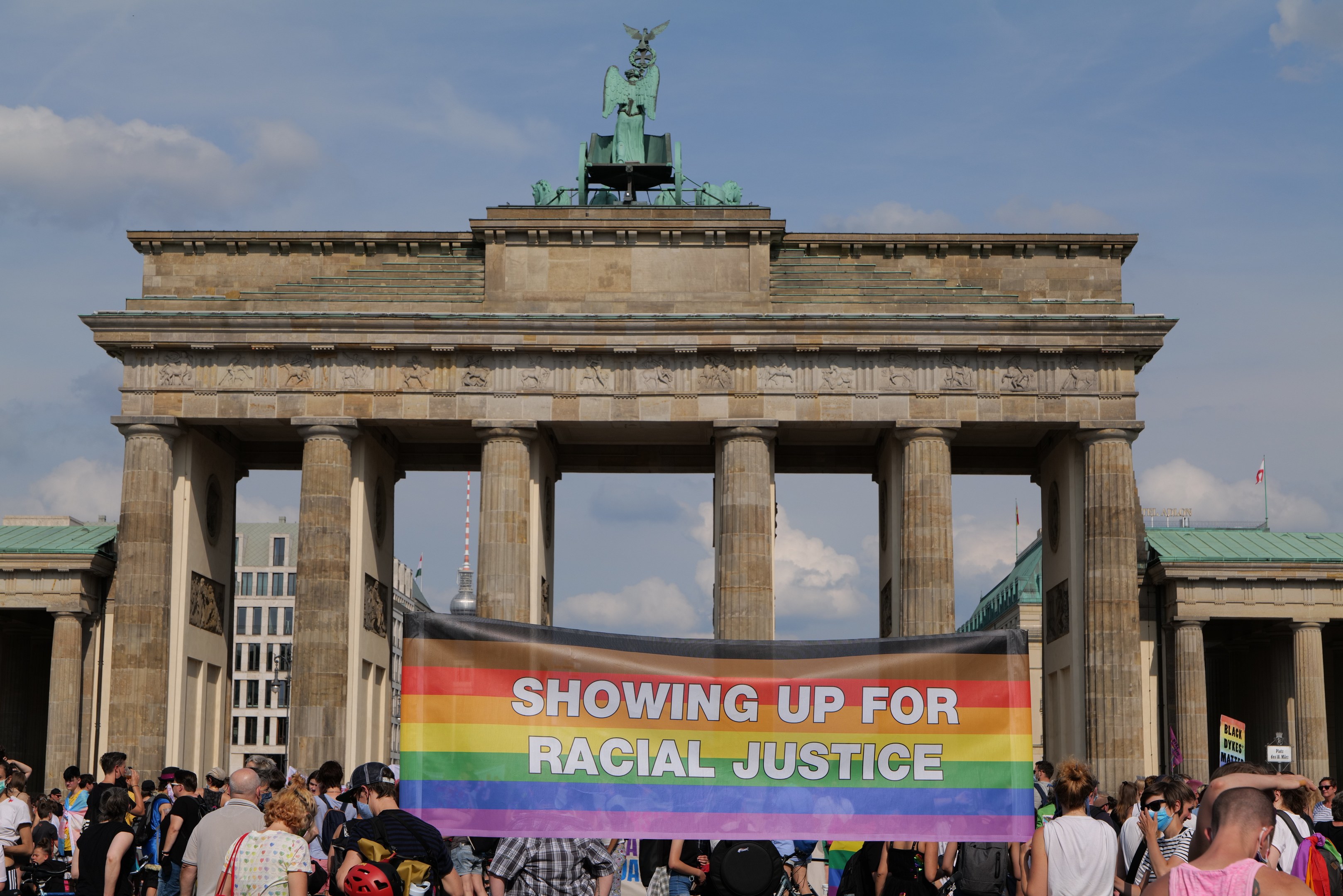 Eine Gruppe von Menschen, die vor dem Brandenburger Tor in Berlin, Deutschland, mit einem Banner mit der Aufschrift "Rassengerechtigkeit" stehen.
