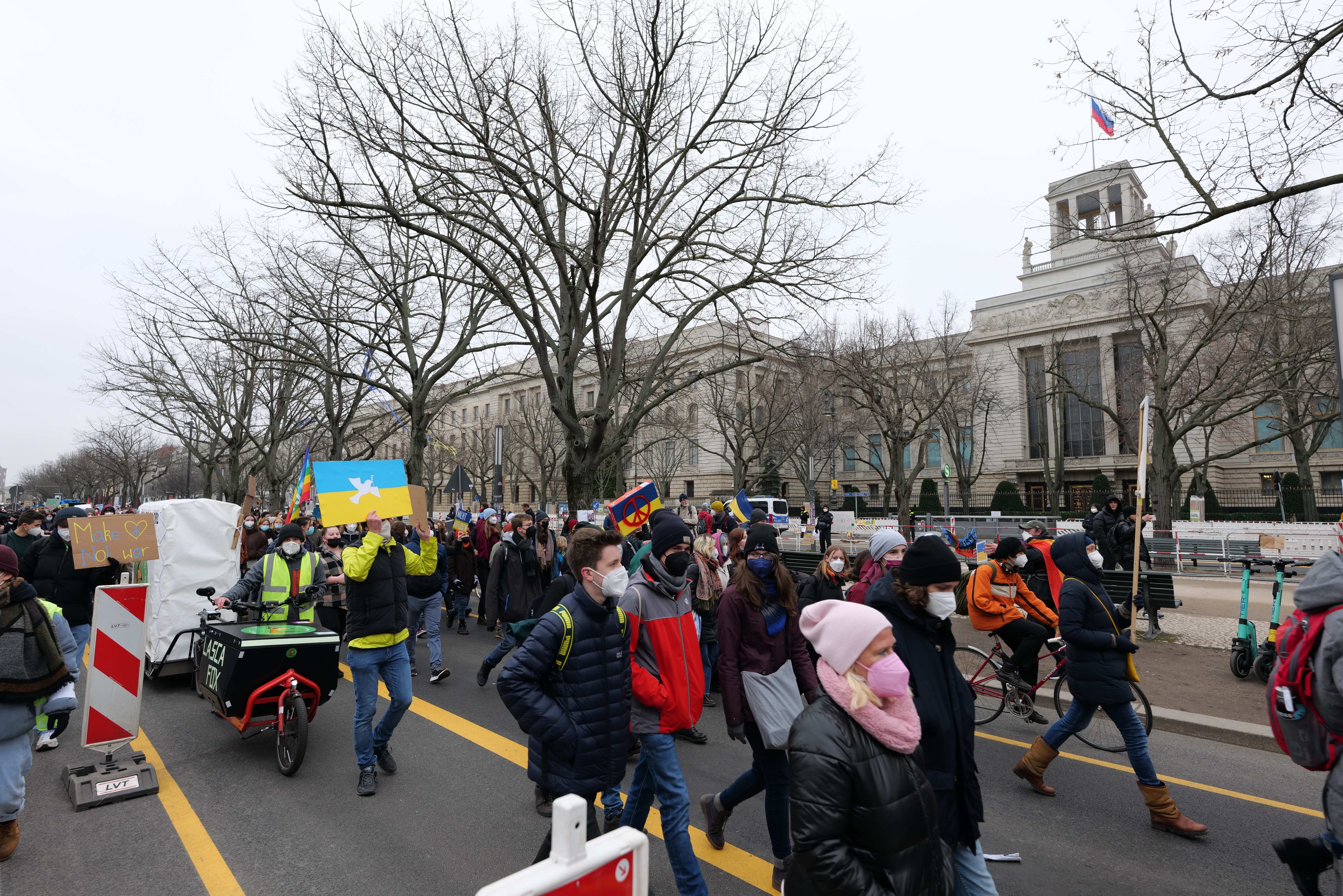 Eine große Gruppe von Menschen marschiert auf einer Straße in Washington, D.C. mit Schildern und Fahrrädern, mit Bäumen und einem Gebäude im Hintergrund unter einem klaren blauen Himmel am 21. Januar 2020.