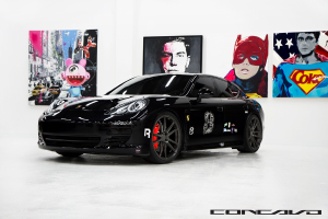 Ein schwarzer Nissan-Sportwagen steht vor Cartoon-Postern, mit einer kleinen Inschrift am unteren Bildrand.