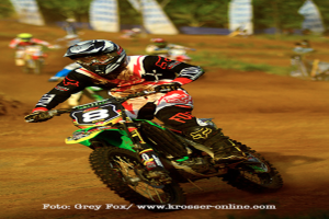 Mehrere Motorradfahrer bei einem Rennen, alle tragen Helme, mit Text am unteren Bildrand.