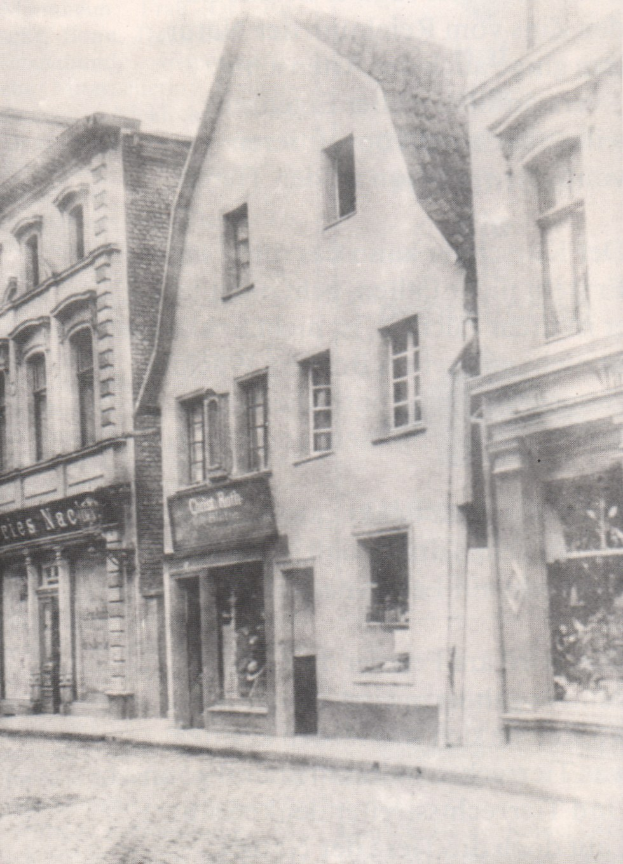 Schwarzes und wei├čes Foto einer Stra├če mit Geb├Ąuden mit Fenstern und Namensschildern, mit einer Stra├če unten.