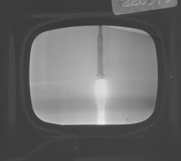 Schwarzes und weißes Foto eines Fernseherbildschirms mit einer Raketenstartszene im Hintergrund und Text oben.