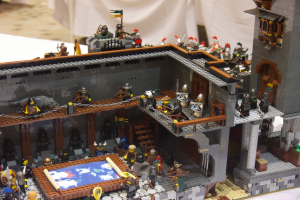 Eine Lego-Königreichszene mit Soldaten, Offizieren und einer Kartenvorlage auf einem Tisch, mit einem weißen Tuch im Hintergrund.