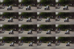 Ein Kind läuft auf einer Straße und zieht einen Einkaufswagen, während zwei Personen Fahrräder halten, Bäume im Hintergrund und ein Gebäude auf der linken Seite.