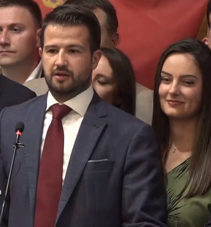 Ein Mann im Anzug spricht an einem Rednerpult mit einem Mikrofon zu einer Menge hinter einem Banner, wahrscheinlich über ein Regierungsverbot von Social Media.