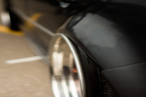 Ein schwarzes Auto fährt auf einer Straße mit einem unscharfen Bereich auf der rechten Seite des Bildes.