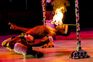 Eine Person schaut auf ein Feuer, das auf einem Stab an Pfählen befestigt ist.