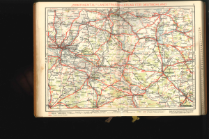 Ein aufgeschlagenes Buch mit einer detaillierten Deutschlandkarte mit Straßen und Autobahnen auf einem dunklen Hintergrund.