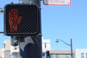 Eine Stadtstraßenszene mit Verkehrspfählen, Verkehrsampeln, Straßenpfählen, Straßenlaternen, Gebäuden und einem klaren Himmel.