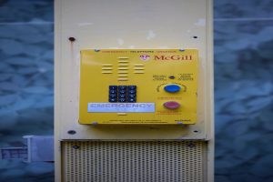 Gelber Notrufknopf an einer Gebäudewand mit Tasten und Text für Notrufe.