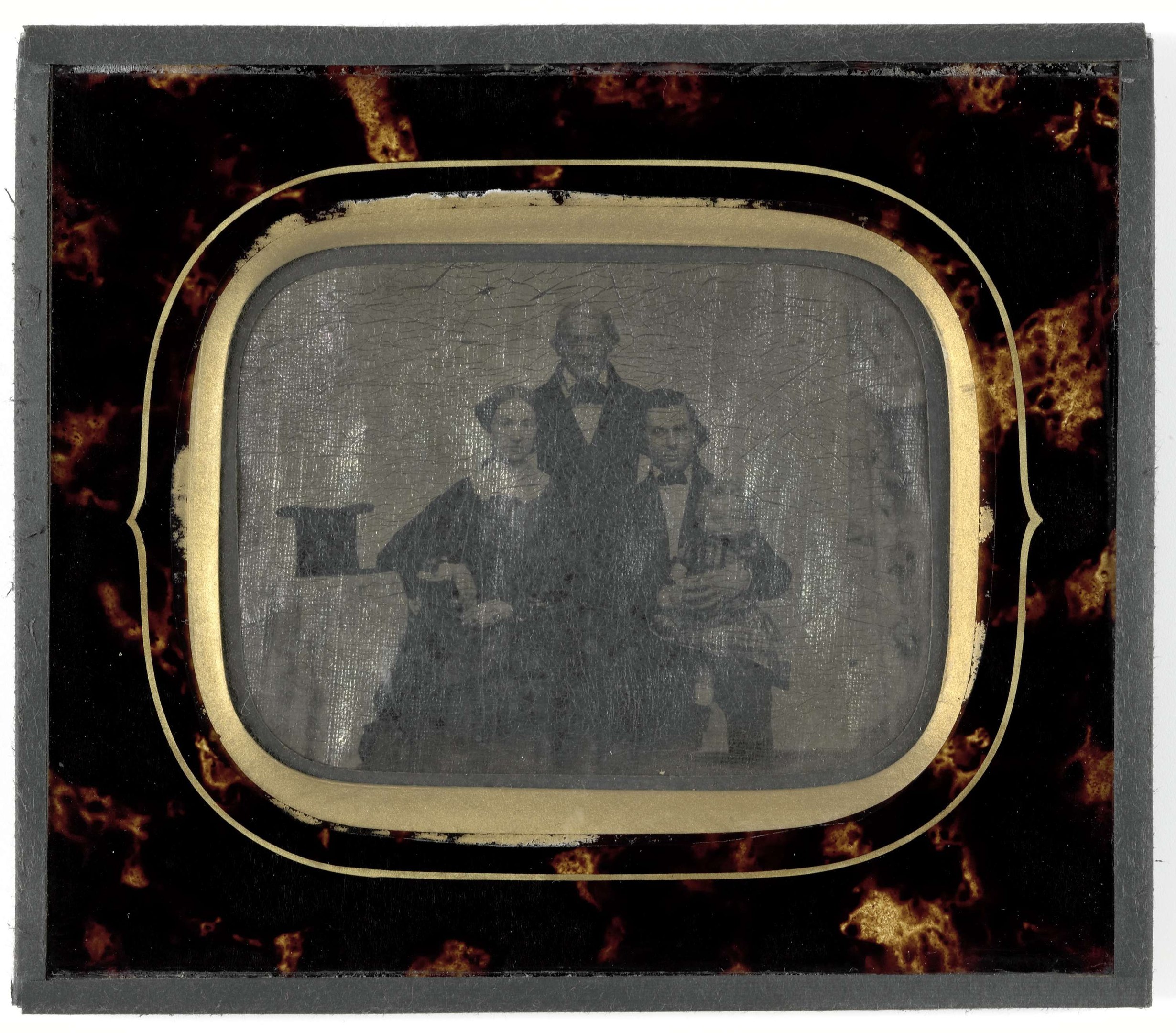 Schwarze-Weiß-Foto eines Mannes in Anzug und Krawatte und einer Frau in unbekannter Kleidung, die vor einem alten Fernseher stehen, beide mit ernsten Gesichtern.