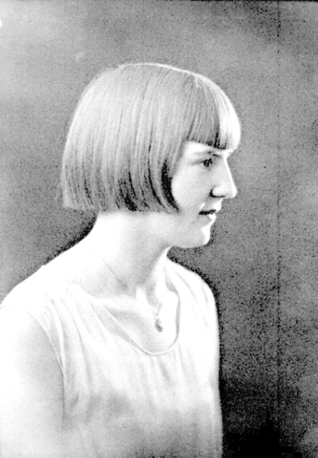 Ein Schwarz-Weiß-Foto einer Frau mit einem kurzen Bob-Haarschnitt, ihr Gesicht ist deutlich zu sehen, mit Augen, die zur Seite blicken und leicht geöffneten Lippen.