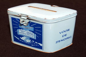 Weißer und blauer Blechspartopf mit einem blauen und weißen Schild, das "Voor de Zending" auf einer schwarzen Oberfläche trägt.