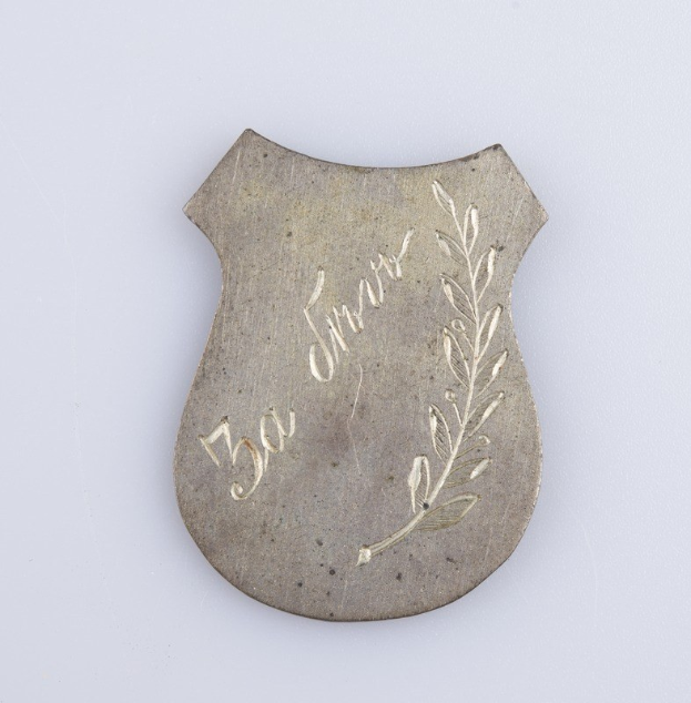 Ein silbergerändertes Abzeichen mit einem Lorbeerkranz, darauf die Inschrift "50. Hochzeitstag" auf einem weißen Hintergrund.