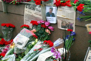 Eine Wand mit einem Blumenstrauß, mehreren Zeitungen und einem Foto einer Person, die eine feierliche Atmosphäre schafft.